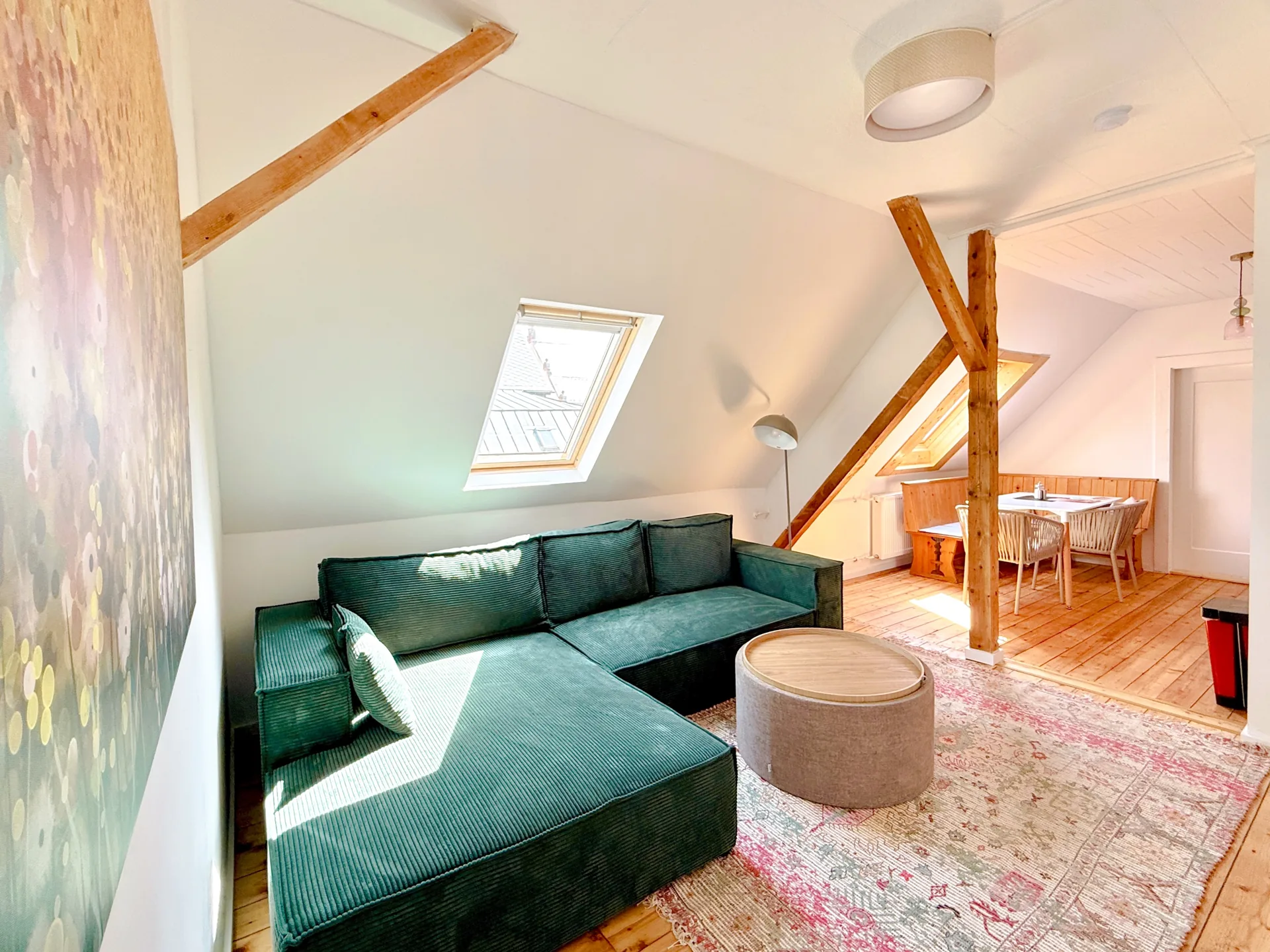 Heller Wohnbereich mit grünem Sofa und sichtbaren Holzbalken